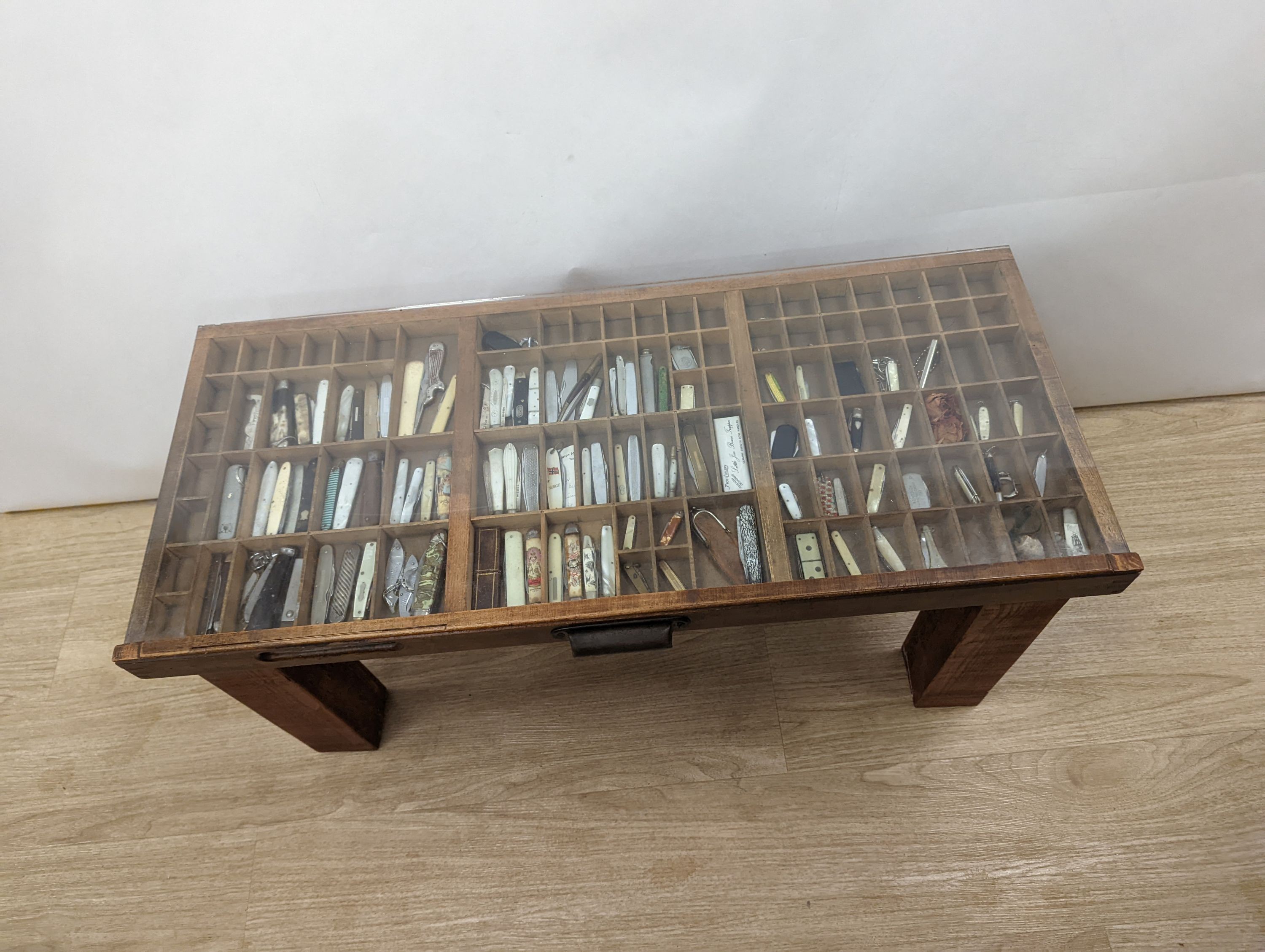 A collection of 19th century and later pen and fruit knives mounted in a coffee table